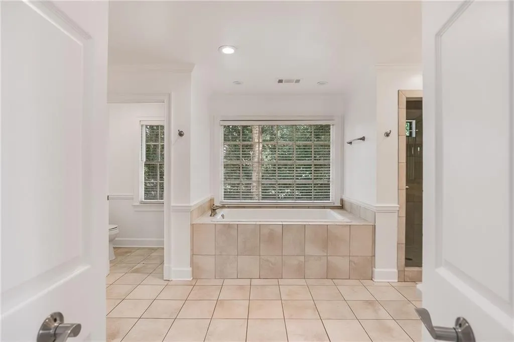 Full bath with light tile patterned floors, a garden tub, recessed lighting, crown molding, and a stall shower