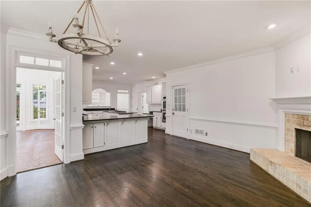 Unfurnished living room featuring crown molding, a chandelier, recessed lighting, dark wood-style floors, and a brick fireplace