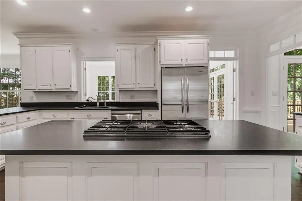 Kitchen with plenty of natural light, a center island, white cabinetry, stainless steel appliances, and ornamental molding