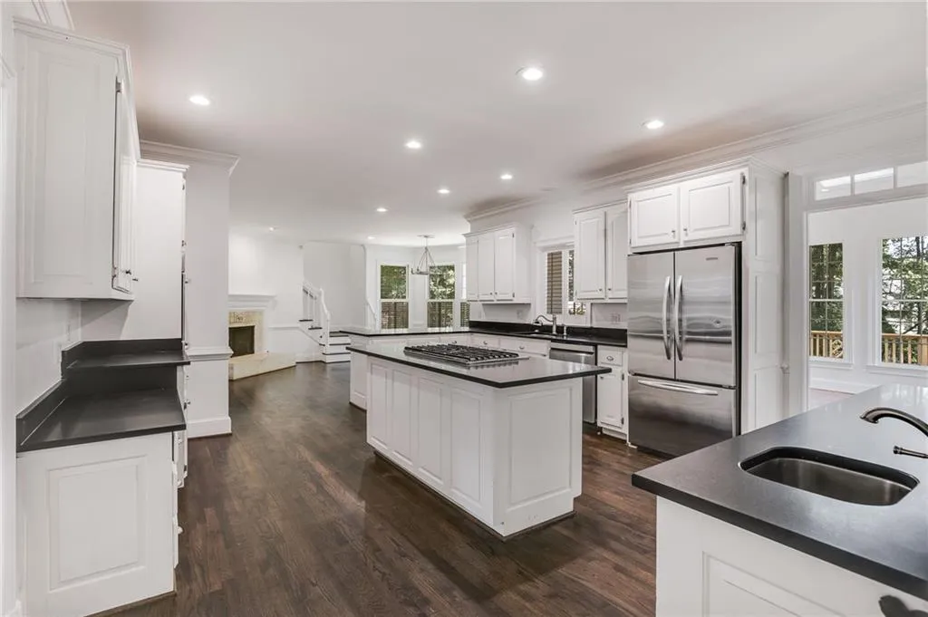 Kitchen with appliances with stainless steel finishes, dark wood-style flooring, white cabinets, recessed lighting, and hanging light fixtures