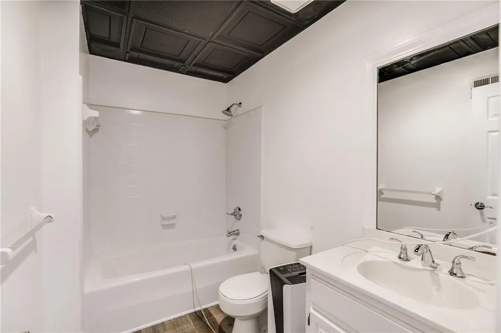 Bathroom with bathing tub / shower combination, vanity, and dark wood finished floors