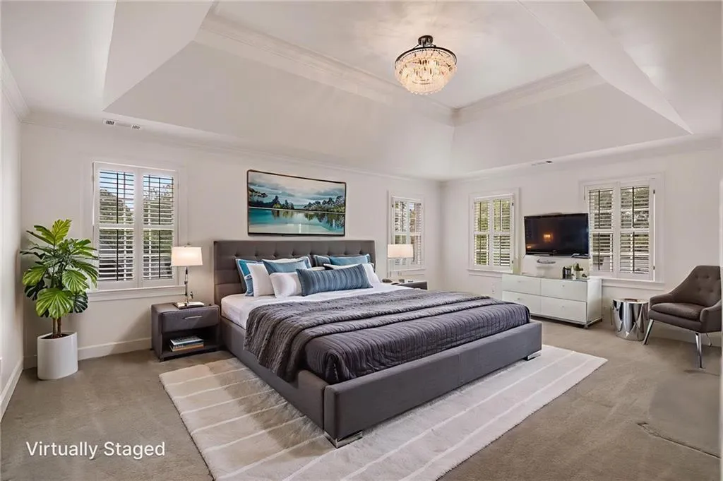 Bedroom featuring a tray ceiling, crown molding, carpet floors, and multiple windows