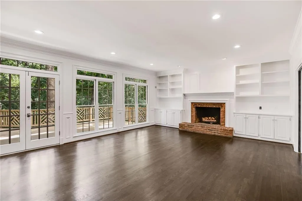 Unfurnished living room featuring built in shelves, dark wood-style floors, recessed lighting, french doors, and a brick fireplace