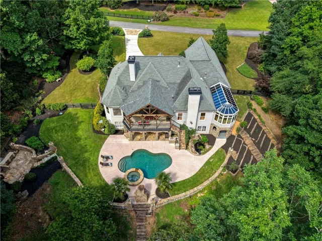 Expansive rear exterior featuring a freeform swimming pool, integrated spa, and surrounding hardscaping