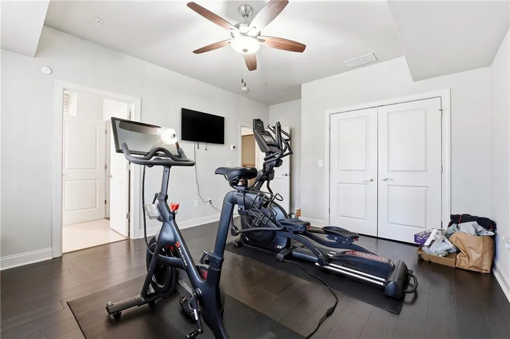 Exercise area with dark wood-style flooring and ceiling fan