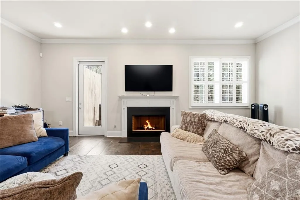 Living room featuring ornamental molding, recessed lighting, hardwood / wood-style floors, and a fireplace with flush hearth