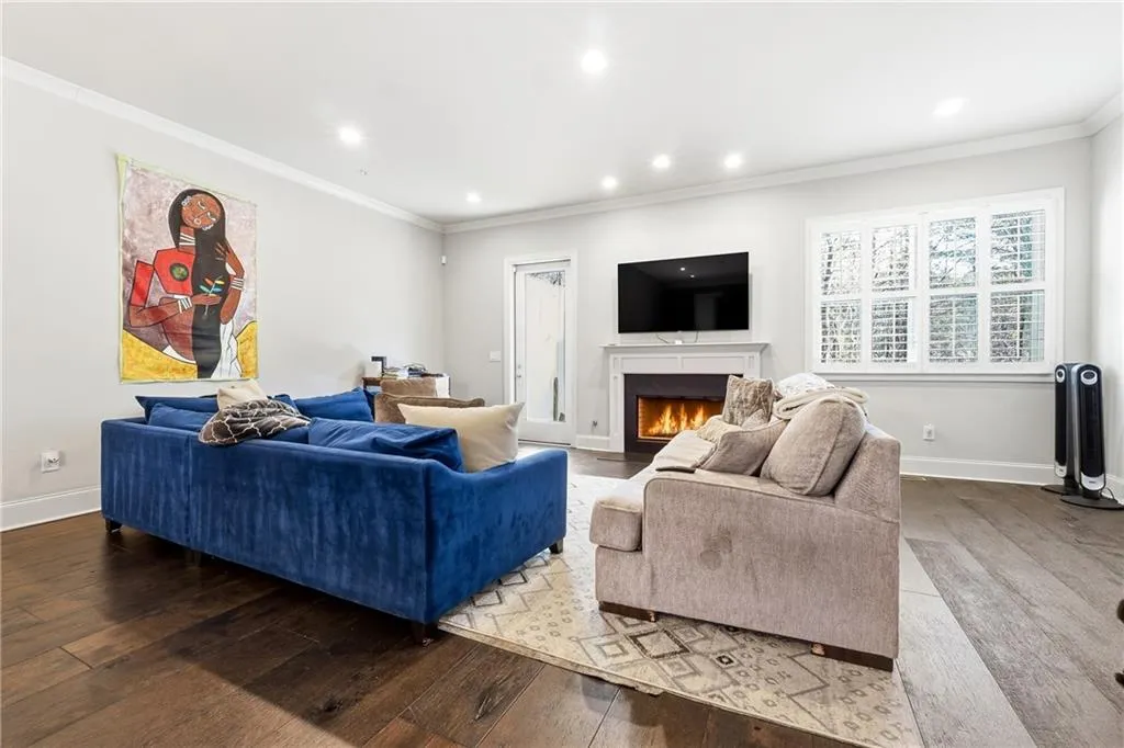 Living area with hardwood / wood-style floors, a fireplace with flush hearth, recessed lighting, and ornamental molding