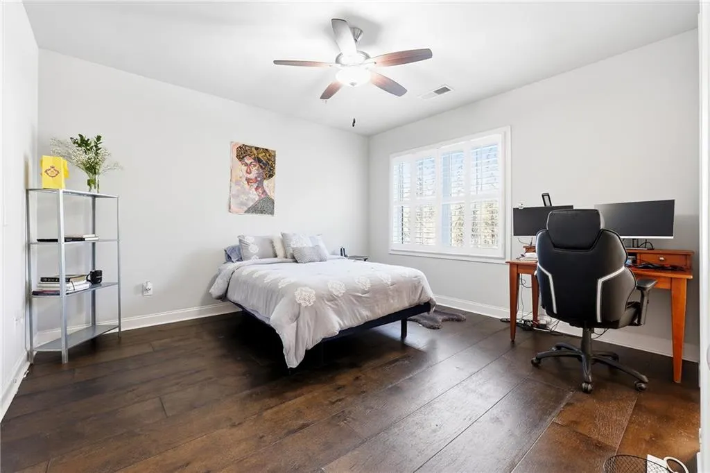 Bedroom with dark wood-style floors, a ceiling fan, and a desk