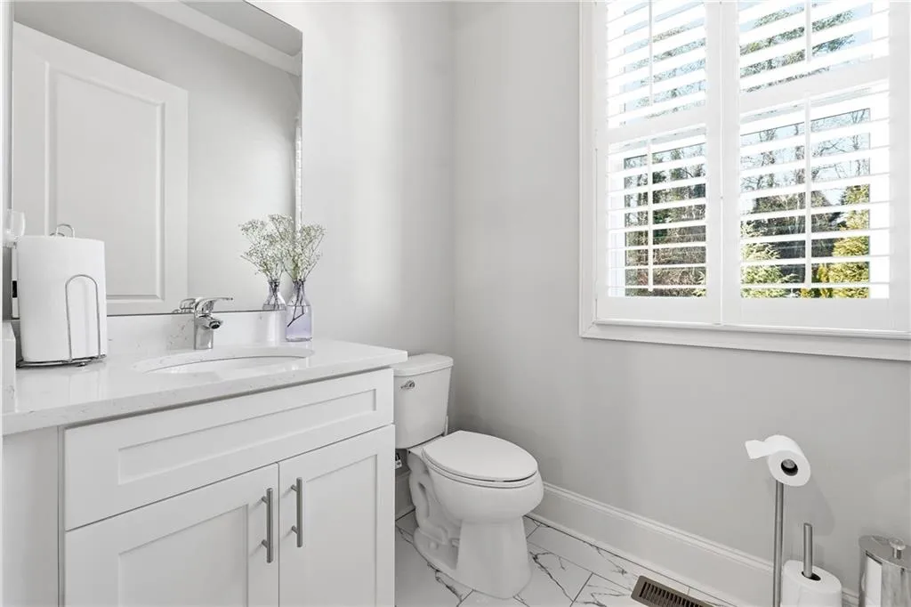 Half bath with light marble finish flooring and vanity