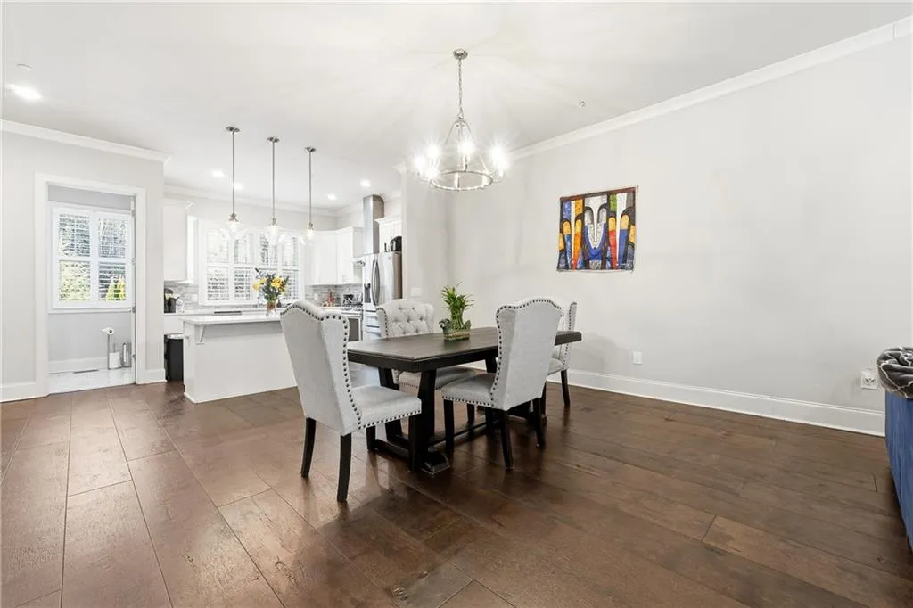 Dining room with ornamental molding, dark wood-type flooring, recessed lighting, and a chandelier