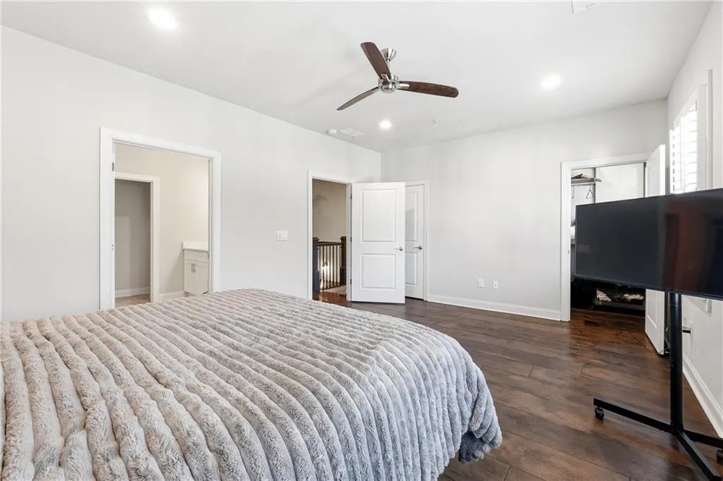 Bedroom with ensuite bathroom, dark wood finished floors, a spacious closet, ceiling fan, and recessed lighting