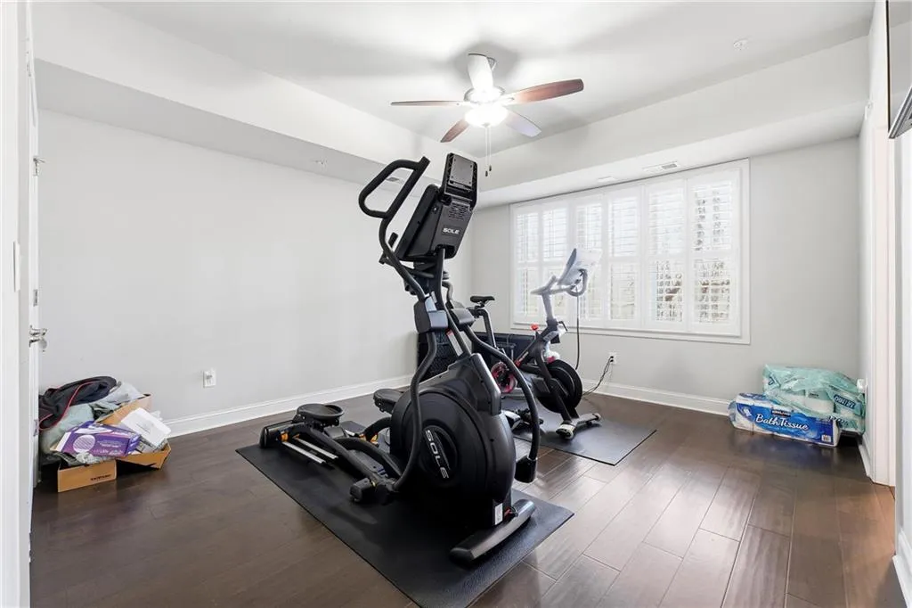Workout area with dark wood-style floors and ceiling fan