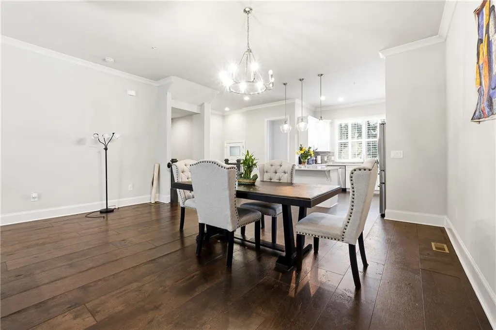 Dining room featuring dark wood-type flooring, ornamental molding, recessed lighting, and a chandelier