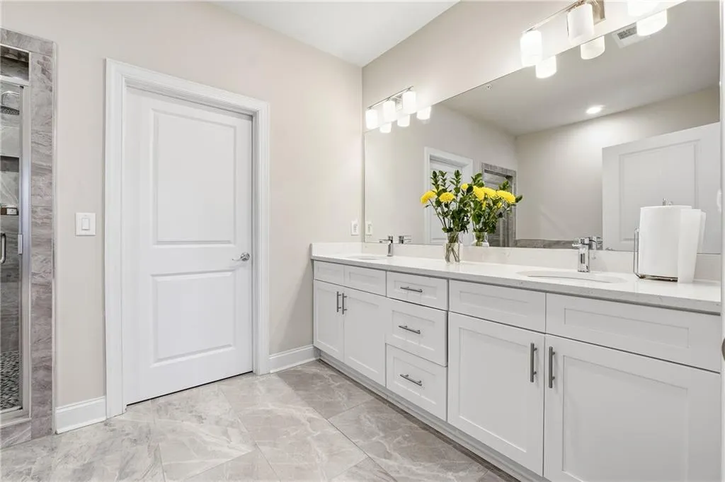 Bathroom featuring double vanity and light marble finish flooring