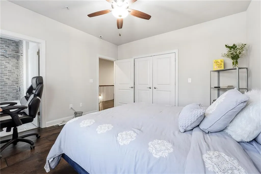Bedroom with a ceiling fan, a desk, dark wood-style floors, and a closet