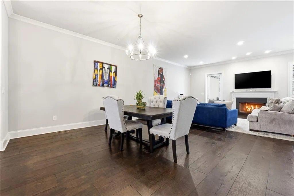 Dining room featuring ornamental molding, a lit fireplace, dark wood finished floors, recessed lighting, and a chandelier