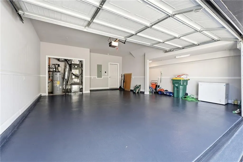 Garage with heating unit, refrigerator, water heater, and electric panel