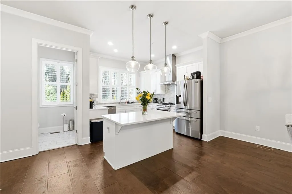 Kitchen with white cabinets, stainless steel appliances, a center island, pendant lighting, and dark wood-style flooring
