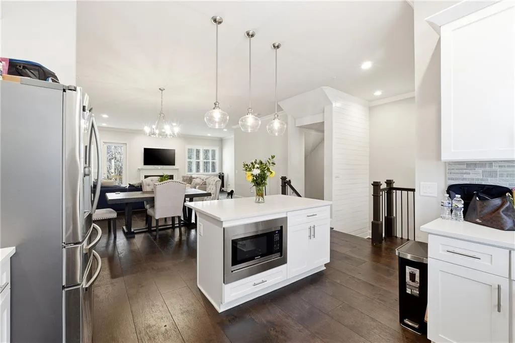 Kitchen featuring stainless steel appliances, open floor plan, white cabinets, a fireplace, and recessed lighting