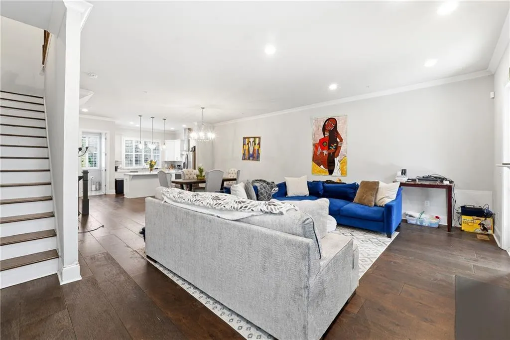 Living room featuring stairway, dark wood-type flooring, a chandelier, recessed lighting, and crown molding