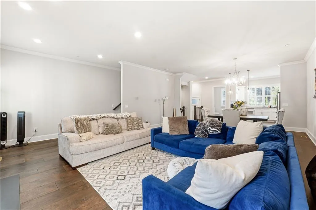 Living area featuring dark wood-style flooring, recessed lighting, ornamental molding, and a chandelier