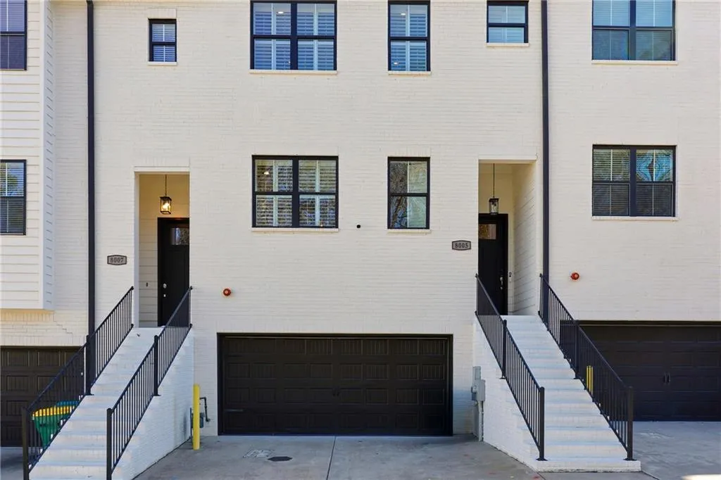 View of front facade featuring a garage, concrete driveway, stairs, and brick siding