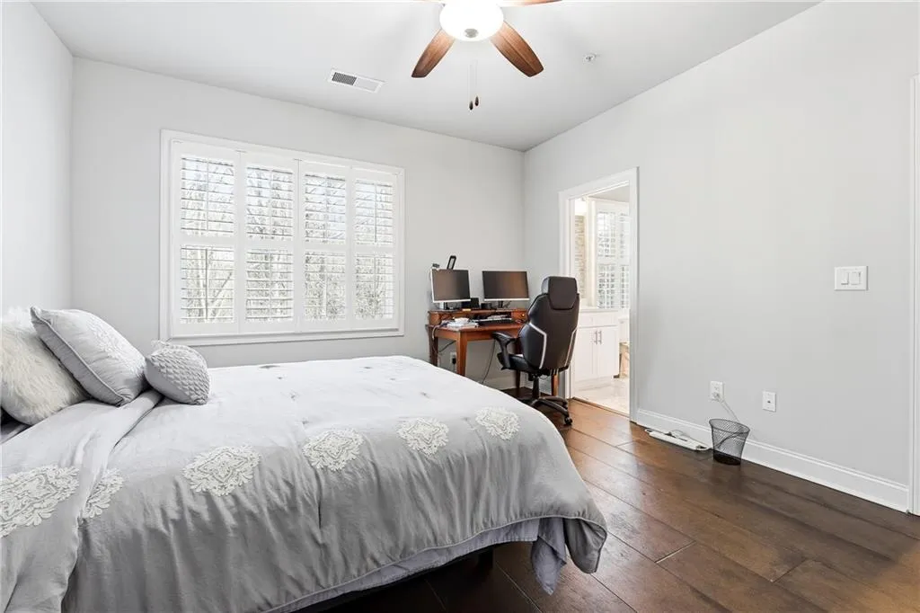 Bedroom featuring hardwood / wood-style flooring, a ceiling fan, an office area, and connected bathroom