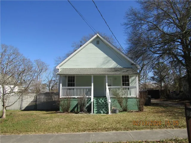 Light green siding exterior with a covered front porch featuring white railing and a gray shingle roof