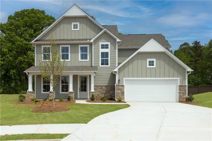 Two-story residence featuring light green siding, white trim, and stone accents