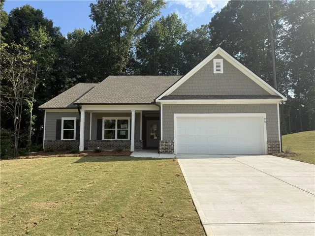 Gray siding exterior with a white garage door, dark shutters, and brick accents