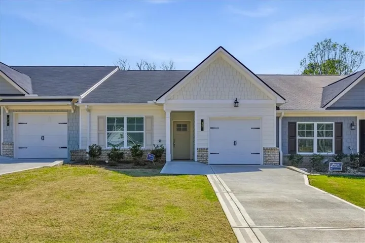 View of front facade featuring a garage, a front lawn, driveway, and roof with shingles