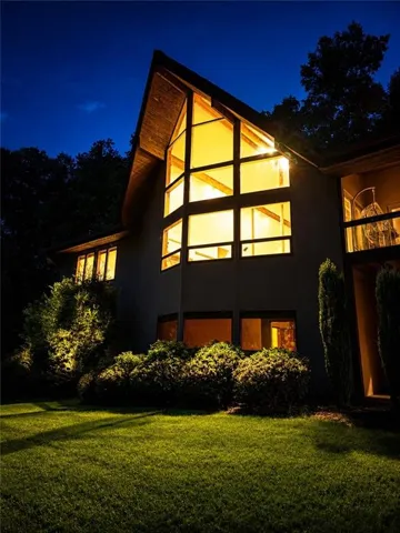 Contemporary architectural design featuring a prominent window wall, an A-frame roofline, and a private balcony
