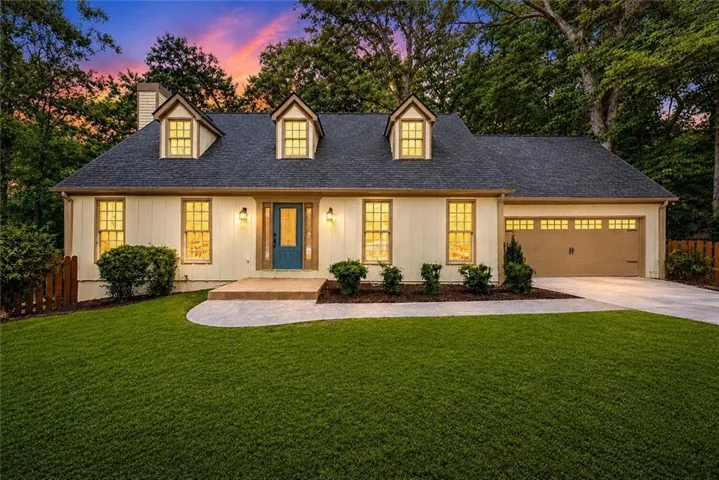 Traditional-style home featuring a dark shingle roof, light-toned siding, and multiple dormer windows