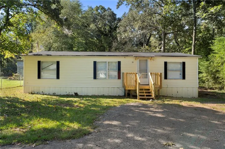 Single-story residence featuring light-colored siding, black window shutters, and a wood entry deck with stairs
