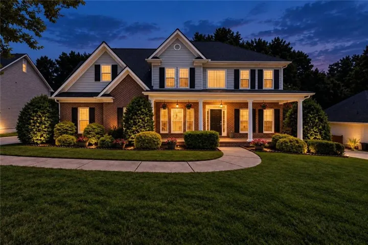 Traditional-style exterior with brick and siding accents, a columned front porch, a gabled roofline, and established landscaping