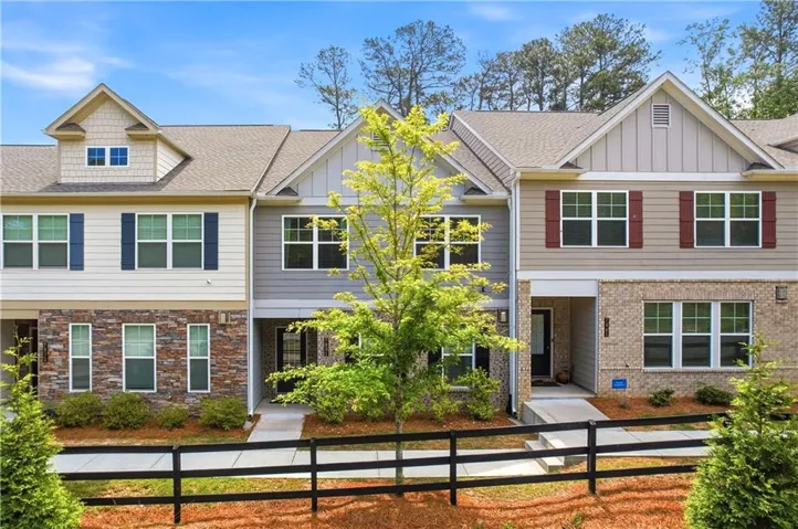 Modern townhome exterior featuring an architectural shingle roof, stone and siding facade, contrasting window shutters, and a prominent front entrance
