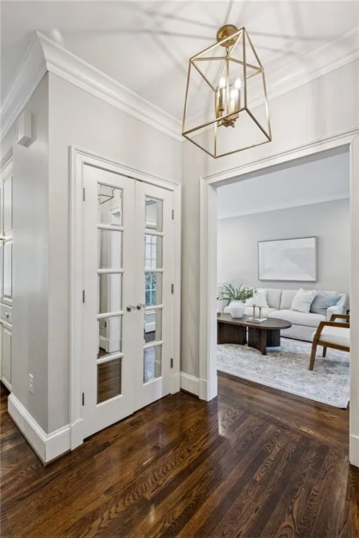 Foyer featuring ornamental molding, dark wood-style flooring, a chandelier, and french doors