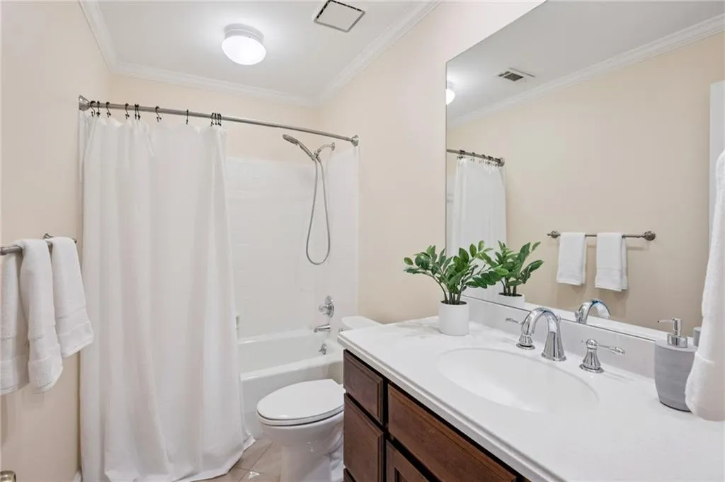 Bathroom with ornamental molding, shower / bath combo, vanity, and light tile patterned floors