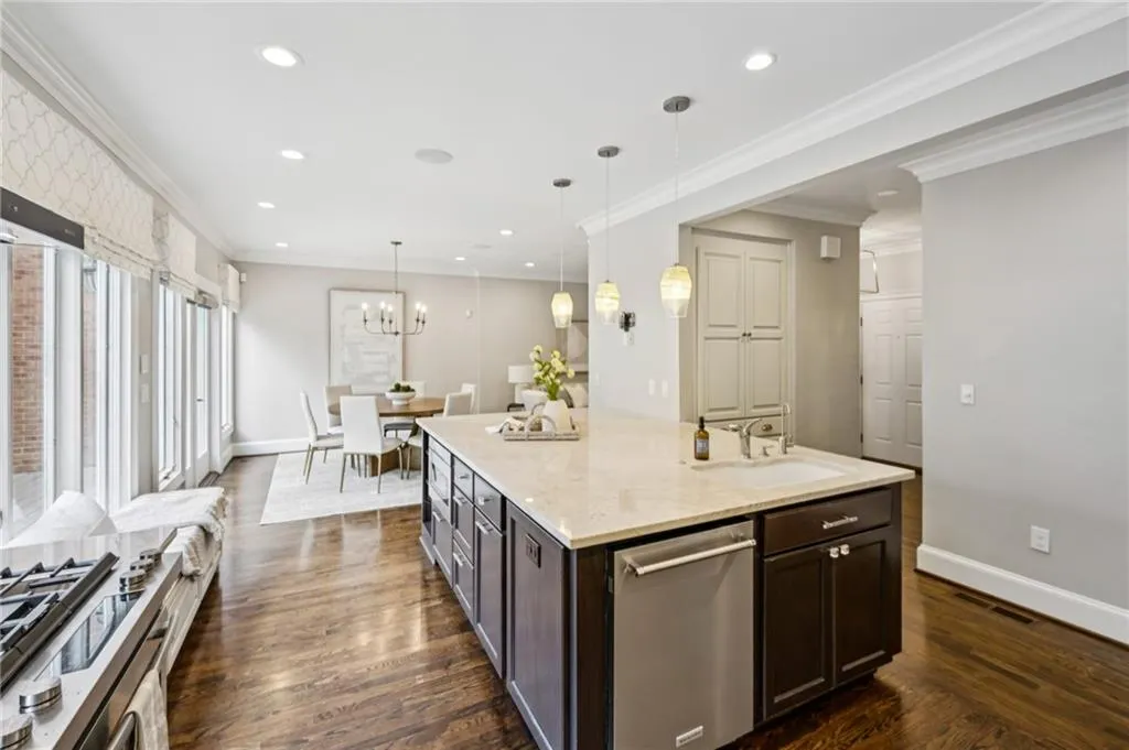 Kitchen featuring dark brown cabinets, crown molding, stainless steel appliances, dark wood-style floors, and decorative light fixtures