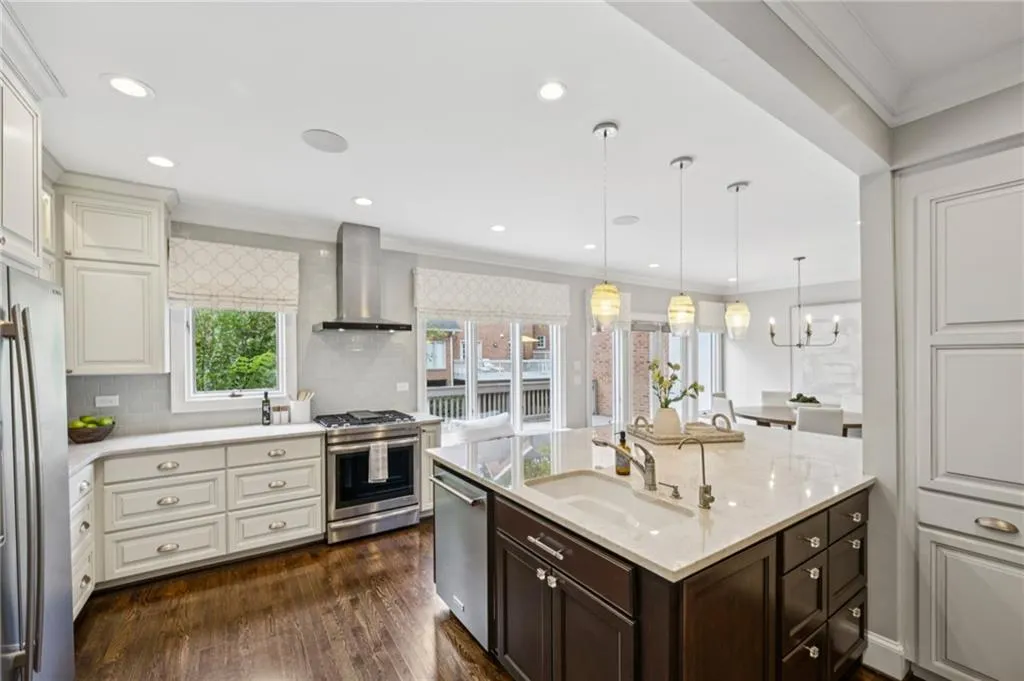 Kitchen with crown molding, hanging light fixtures, decorative backsplash, stainless steel appliances, and dark wood-style floors