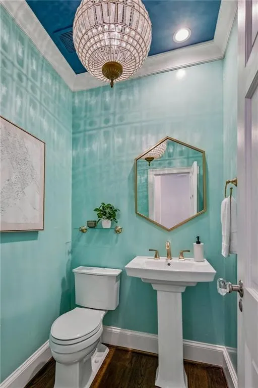 Bathroom with dark wood-style flooring, crown molding, and recessed lighting