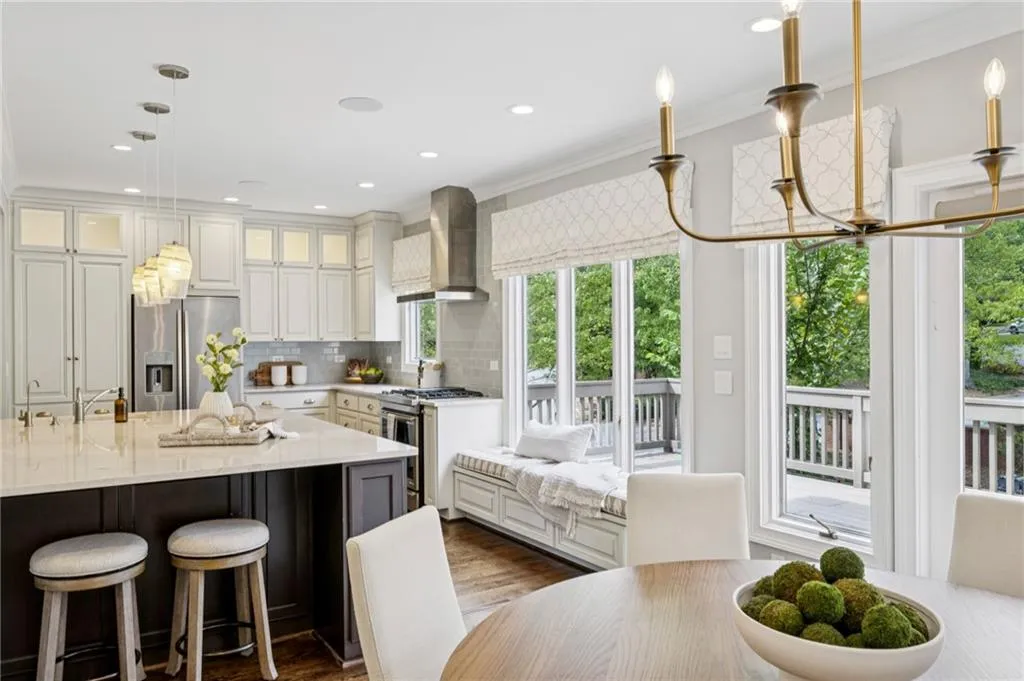 Kitchen featuring a kitchen bar, stainless steel appliances, tasteful backsplash, pendant lighting, and wall chimney exhaust hood
