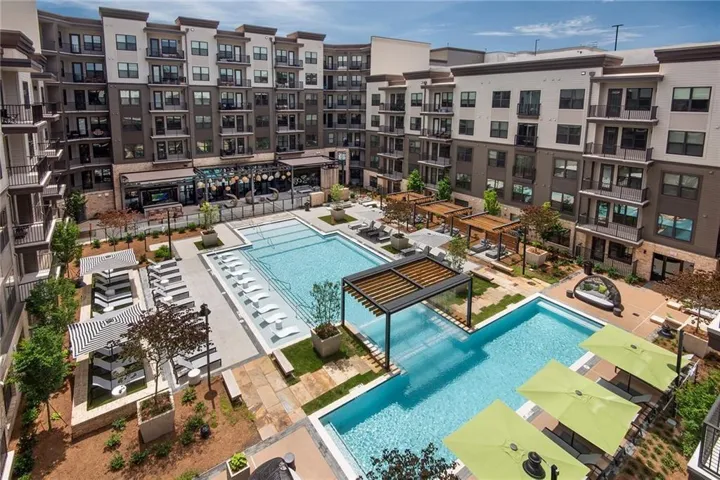 Expansive courtyard featuring two swimming pools, multiple pergolas, and landscaped planter beds