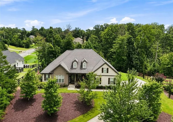 Traditional-style residence featuring a dormered roofline, brick and siding exterior, and a concrete driveway
