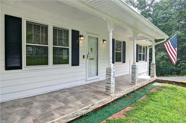Covered front porch featuring decorative columns with stone bases and a textured surface