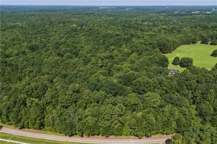 Expansive wooded acreage with a cleared pasture and a single-story residence