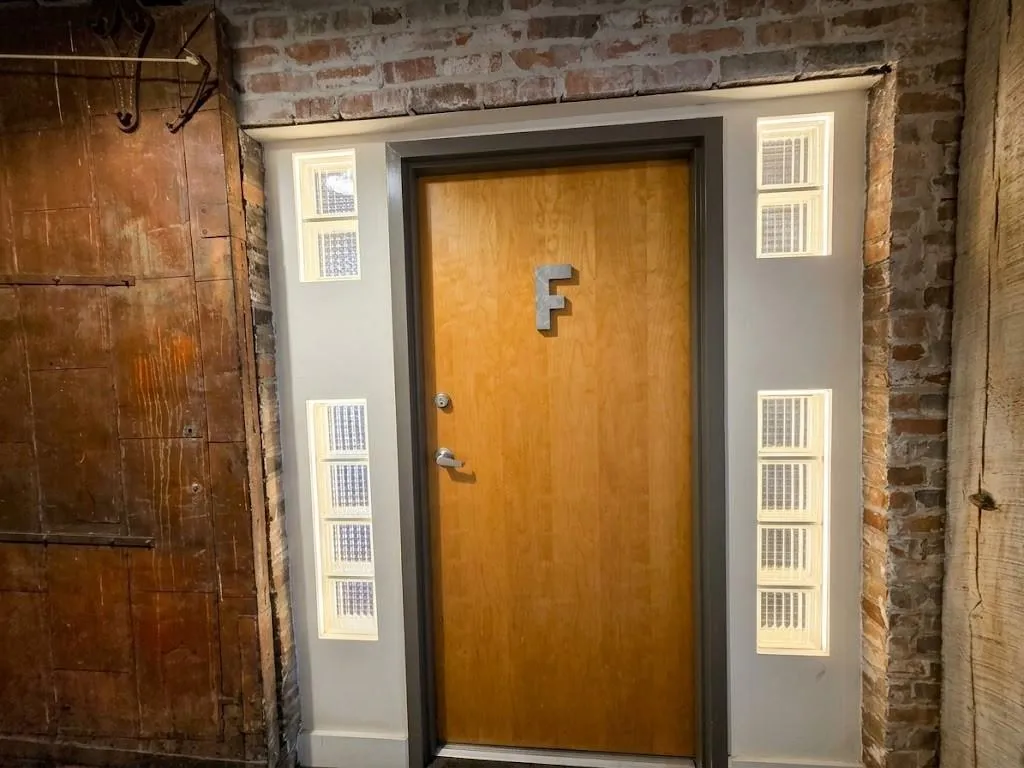 Light wood-finish door with a dark trim, flanked by glass block windows