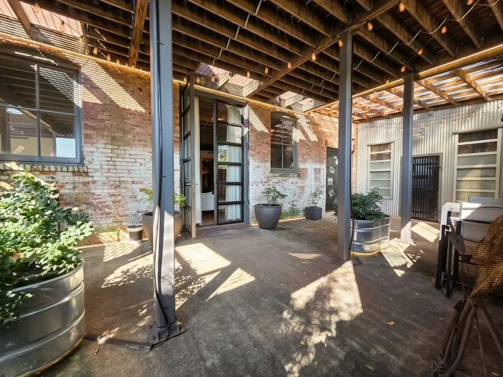 Covered outdoor patio with exposed wood beam ceiling, concrete flooring, and industrial-style metal support pillars