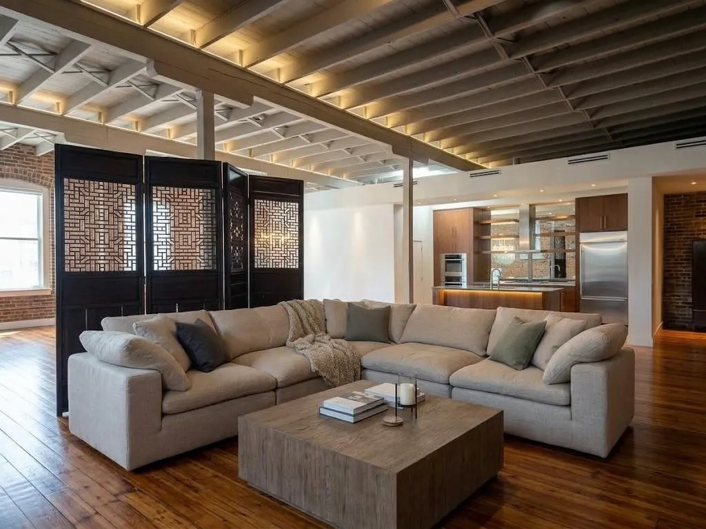 Exposed wood ceiling beams with recessed lighting, exposed brick wall accent, wood-finish flooring, built-in kitchen cabinetry, and stainless steel kitchen appliances