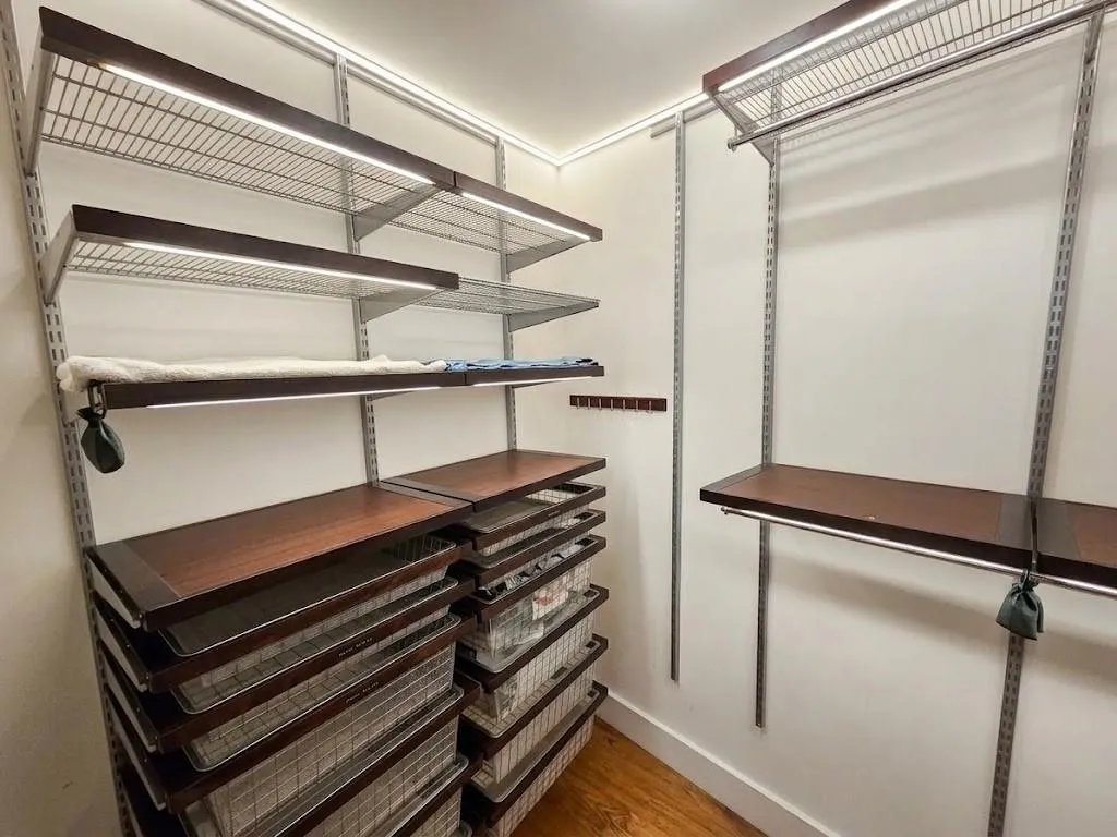 Custom closet system featuring dark wood-finish shelving, wire racks, and integrated lighting